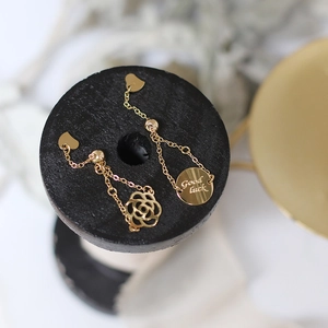 Macro shot of 14K gold-plated earring with rose design and Good luck engraved charm