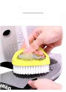 Spazzola ergonomica gialla pulisce scarpe da ginnastica grigio scuro nel lavandino