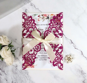 Detail of laser cut purple glitter wedding invitation with beige satin ribbon bow