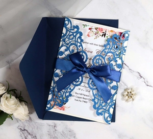 Detail of laser-cut navy glitter invitation with ribbon bow and envelope on marble