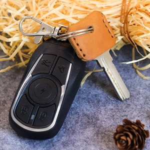 Macro shot of handcrafted brown leather key case with metal keyring and rustic stitching