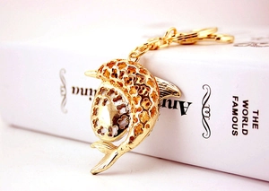 Macro detail of a golden dolphin keychain with hollow patterns on a book background