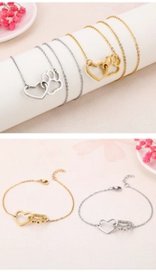 Détail des bracelets avec breloques cœur et patte en or et argent sur décor rose