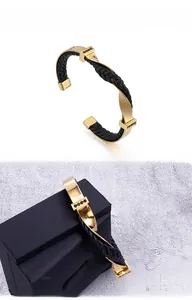 Dettaglio del bracciale ritorto in acciaio dorato con cordino nero e pietre incastonate