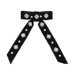 Close-up of velvet bow hair clip featuring sparkling rhinestones and pearl flower details