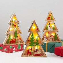 Three wooden Christmas tree lights with warm LEDs on gift boxes, deer and snowman carvings