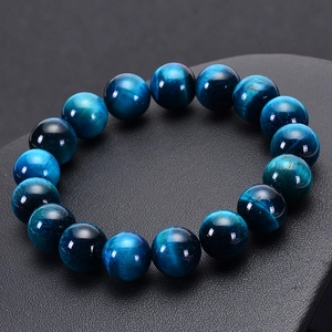 Macro shot of natural blue tiger eye stone beads bracelet on a black textured display