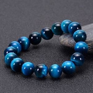 Macro shot of natural blue tiger eye stone beads bracelet with cat-eye effect on dark stone