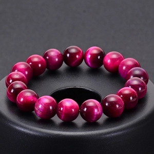 Macro shot of rose red tiger eye stone beads showing polished cat eye optical effect