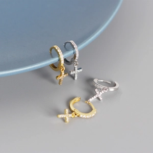 Close-up of gold and silver S925 sterling silver cross hoop earrings with sparkling stones