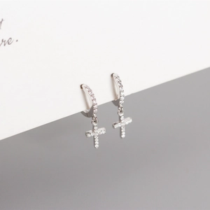 Close-up of silver geometric cross earrings with sparkling zircons on a card