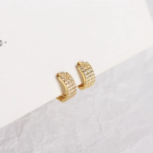 Macro view of gold S925 silver huggie earrings with three rows of pave-set cubic zirconia