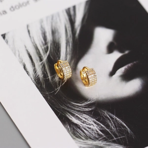 Macro shot of gold-plated geometric hoop earrings with sparkling micro-pave zircons