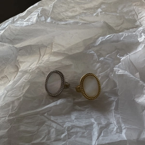 Macro detail of retro oval shell rings in gold and silver finish on textured paper