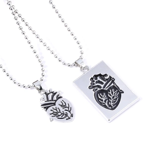 Matching anatomical heart couple necklaces with silver pendants and bead chains on white base