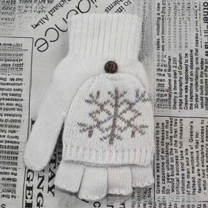Détail de gants en tricot blanc avec motif flocon gris et bouton rouge décoratif