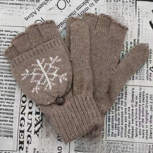 Détail de gants tricotés marron avec motif flocon de neige blanc et bouton décoratif