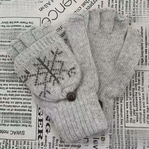 Gros plan de mitaines en tricot gris clair avec motif flocon de neige et bouton