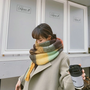 Detail of colorful rainbow plaid scarf with thick fringe worn in a cozy cafe setting
