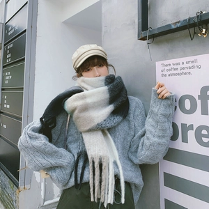 Detail of gradient grey and beige plaid scarf with woven fringe and soft knit texture