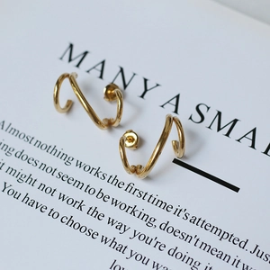 Macro shot of 18K gold plated spiral line stud earrings with a polished geometric finish