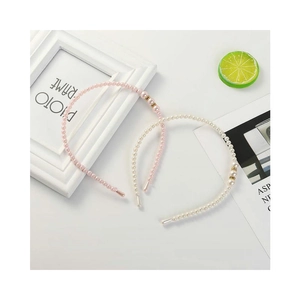 Pink and white pearl headbands for girls with small gold accents on a white desk