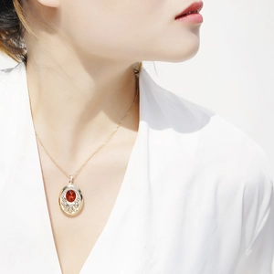 Dettaglio della collana medaglione ovale vintage con gemma rossa indossata da una modella