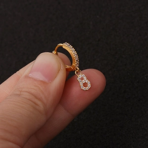 Goldene Creolen mit Zirkonia-Anhänger Nummer 8, gehalten von Hand auf dunklem Grund