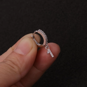 Detailaufnahme eines silbernen Ohrrings mit Zirkon-Anhänger in Form der Zahl 7
