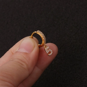 Makroaufnahme eines goldenen Ohrrings mit Zirkonia-Steinen und Anhänger in Form der Zahl 5