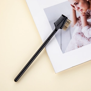 Detail of dual-ended eyebrow comb and eyelash brush with black wooden handle