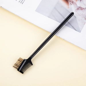 Close-up of professional dual-ended eyebrow brush and lash comb with sleek black handle