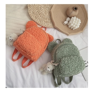 Détail de sacs à dos en laine d'agneau avec oreilles d'ours et breloques en orange et vert