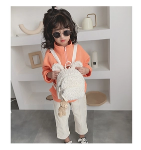 Détail d'un sac à dos blanc en peluche pour enfant avec oreilles de lapin et ours