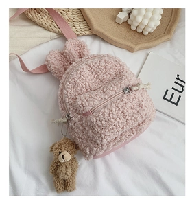 Détail d'un sac à dos rose en laine d'agneau avec oreilles de lapin et charme d'ours brun