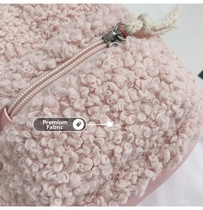 Détail de la texture peluche rose avec fermeture éclair argentée et cordon en coton
