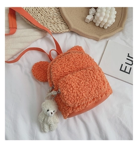 Détail d'un sac à dos en peluche orange avec oreilles d'ours et porte-clés