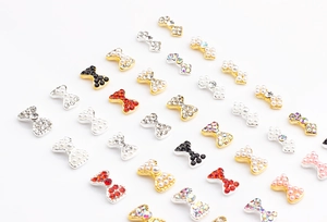 Détails de bijoux d'ongles en forme de nœuds avec perles et strass sur fond blanc