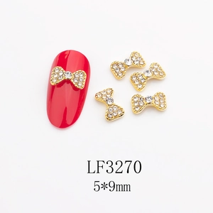Détails des bijoux d'ongles nœuds dorés 5x9mm avec perles sur une manucure rouge