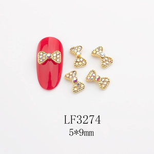 Gros plan de bijoux d'ongles en forme de nœud doré avec strass irisés et taille 5x9mm