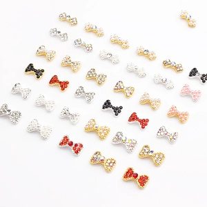 Détail de charmes pour ongles en alliage avec perles et strass colorés sur fond blanc