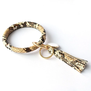 Detail of snake skin print PU leather bangle keychain with tassel and gold ring