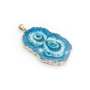 Macro shot of blue agate slice pendant with gold-plated edges and natural ring patterns