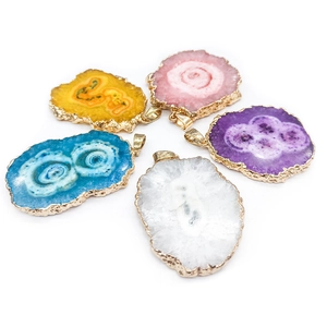 Detail of natural crystal agate pendants in multiple colors with gold-plated edges