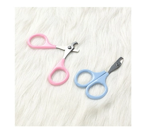 Detail view of pink and blue stainless steel pet nail clippers on a soft white plush background