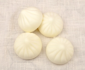 Detailed top view of four cream-colored squishy bun toys on white textured cloth
