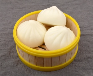 Macro shot of three realistic steamed bun toys with detailed texture in a bamboo steamer