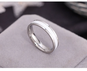 Detailed view of silver stainless steel ring with white enamel inlay on a grey jewelry stand