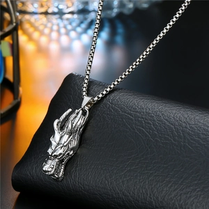 Detail of a silver punk dragon pendant on a box chain over black leather background