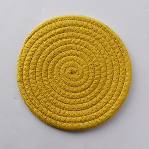 Close-up of a yellow circular woven cotton heat-resistant coaster with spiral texture
